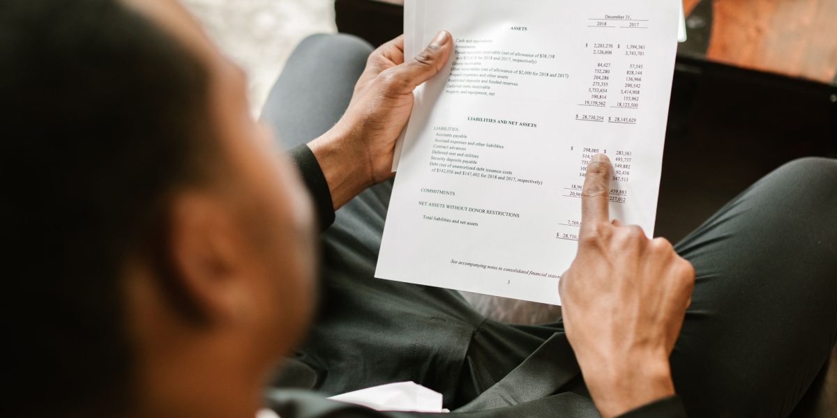 A person carefully reviewing financial documents for a high-value property investment.