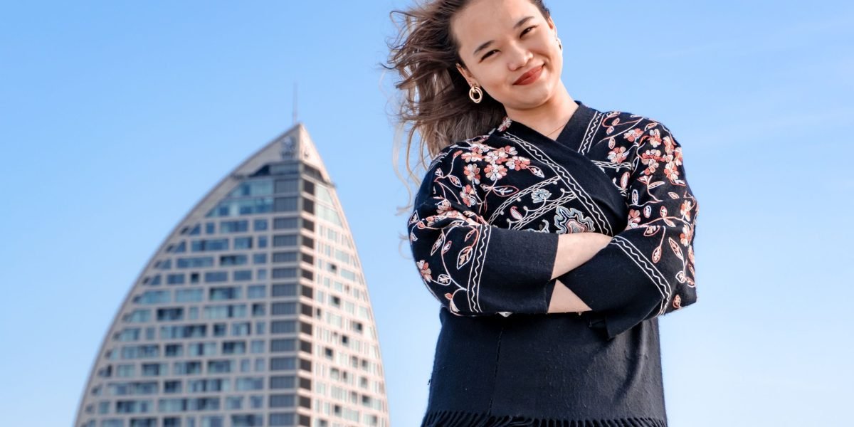 A confident professional smiling with a modern city skyline in the background, symbolizing career ambition in Dubai.